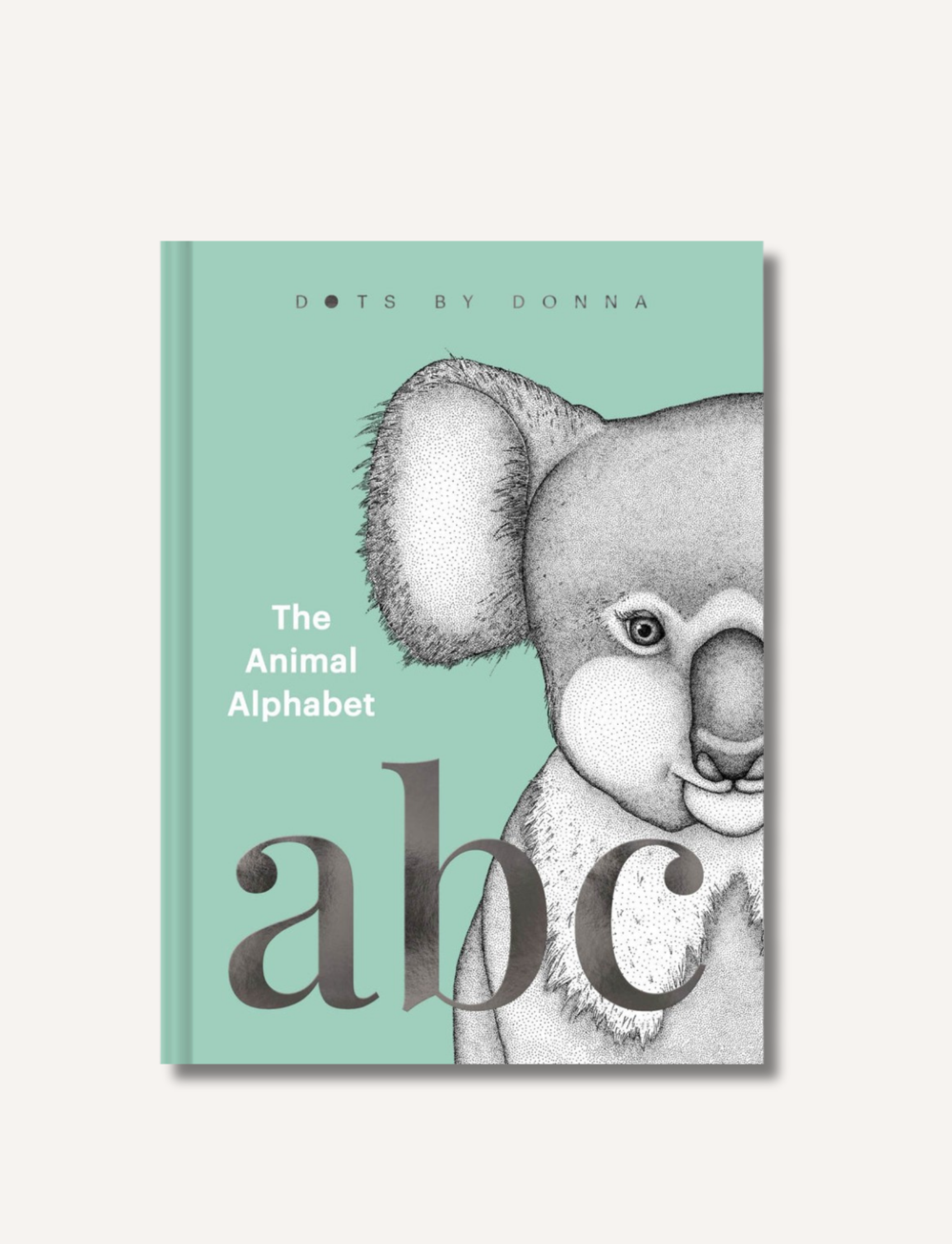 The children's gift book, "Dots by Donna - The Animal Alphabet," published by Lake Press, showcases dot art illustrations and a cover featuring a gray koala against a green backdrop. The large letters "abc" are prominently displayed in the foreground, with the author's name, Dots by Donna, noted at the top.