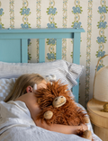 Henry The Highland Cow, by Nana Hutchy, is a soft toy that looks like a shaggy brown highland cow with long hair, beige hooves, horns, and a smiling face. This children's soft toy sits upright against a plain white background and is perfect for cuddles and play.