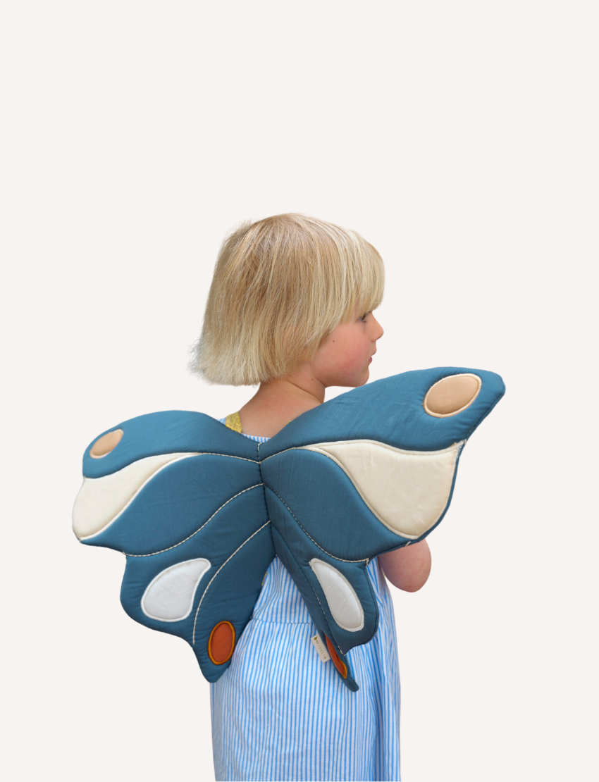 The "Wings - Butterfly Blue Spruce" by Fabelab is a fabric wall decoration in the shape of butterfly wings, featuring patches of teal, beige, white, and brown on a white background. Its symmetrical design makes it perfect for pretend play or as a whimsical kids' costume accessory.