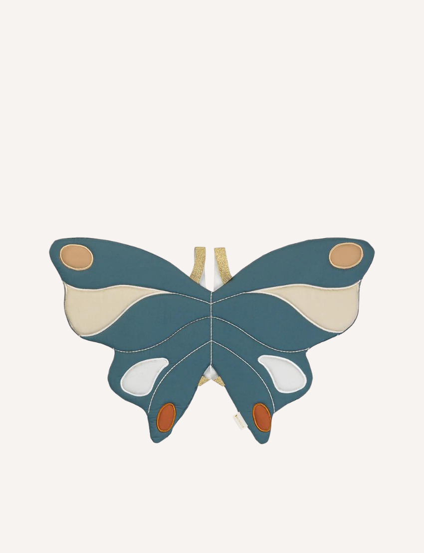 The "Wings - Butterfly Blue Spruce" by Fabelab is a fabric wall decoration in the shape of butterfly wings, featuring patches of teal, beige, white, and brown on a white background. Its symmetrical design makes it perfect for pretend play or as a whimsical kids' costume accessory.