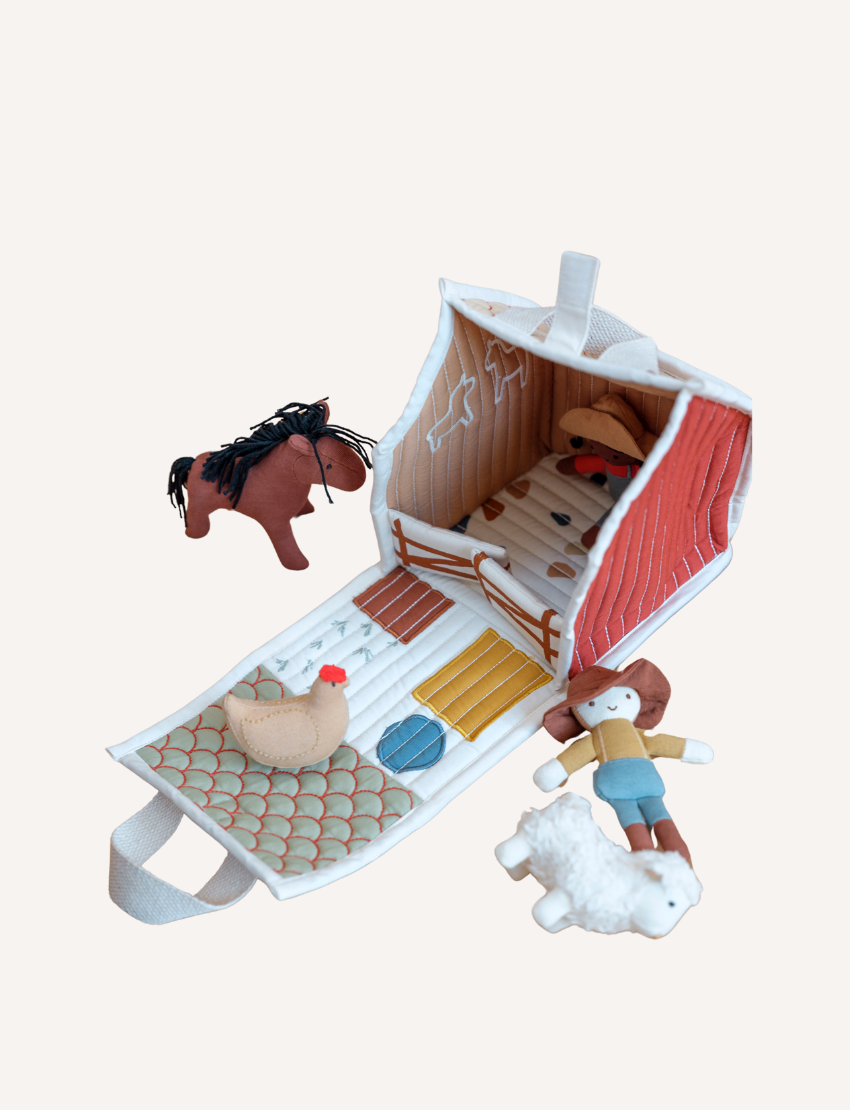 Introducing the Fabric House - Little Farm by Fabelab: a charming toy set made from organic cotton. This delightful children’s playhouse barn features an open front and comes with small plush animals and figures, including a horse, chicken, person, and sheep. The barn is adorned with farm-themed illustrations that spark imaginative play and includes a convenient handle for easy carrying.