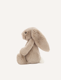 Introducing the Bashful Bunny by Jellycat, a charming plush toy shaped like a beige rabbit with long, floppy ears. This endearing bunny features a pink nose and inner ears, along with a content expression on its face. Made with Jellycat's signature soft fur, Bashful Bunny is posed sitting upright against a plain white background—making it the perfect gift!