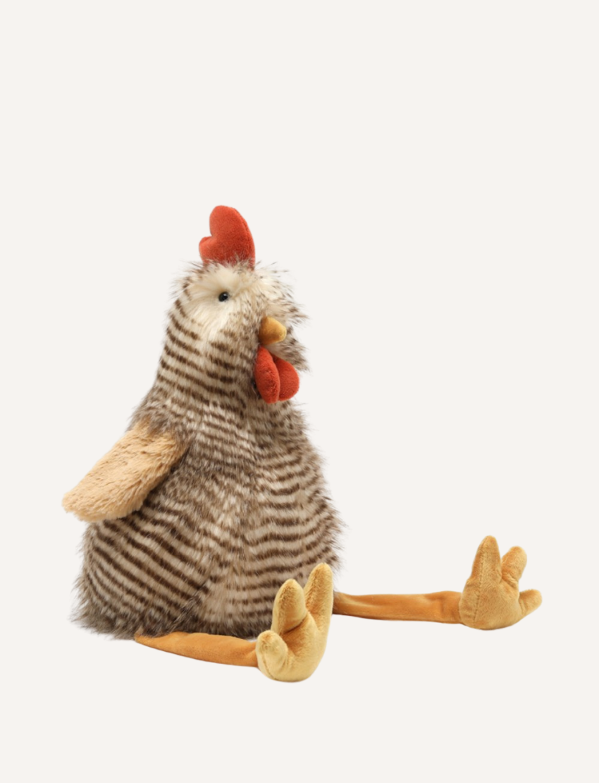 Introducing Rupert The Rooster by Nana Huchy, a delightful stuffed plush toy that captures the charm of a chicken with its striped brown and white feathers, vibrant red comb and wattles, and cheerful yellow legs and feet. Perfect for sparking imagination and laughter during playtime, Rupert sits with his legs stretched out in front.