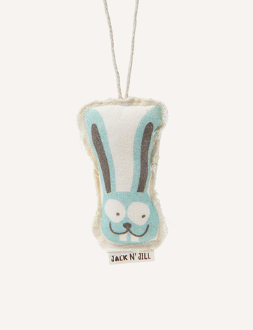 The Bunny Tooth Keeper, by Jack N' Jill, is a plush toy crafted from organic cotton. It features a printed image of a smiling blue rabbit and hangs by a string. The fabric boasts a soft, slightly worn texture, and a small tag at the bottom displays the brand name "Jack N' Jill." This product makes the perfect gift for any Tooth Fairy visit.