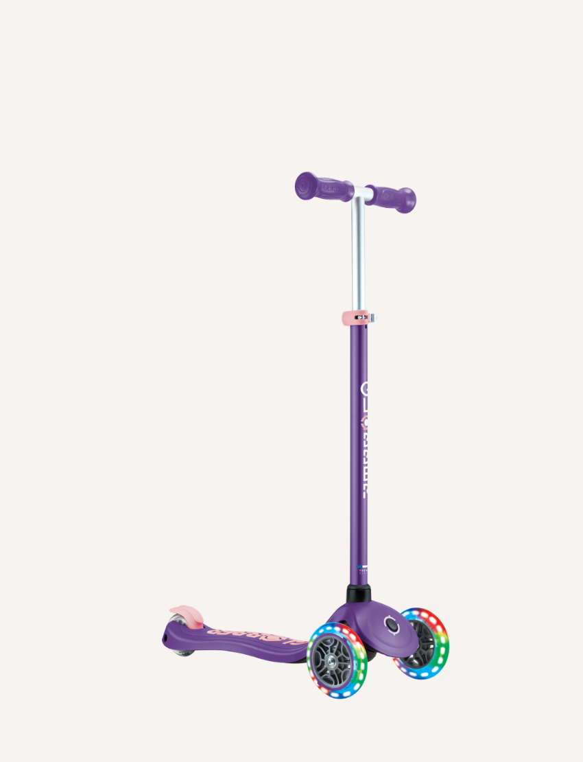 Introducing the PRIMO PLUS with Lights by Globber: a stylish purple three-wheeled kick scooter featuring a sturdy metal handlebar and vibrant light-up wheels. The deck is expertly designed to provide balance and stability.