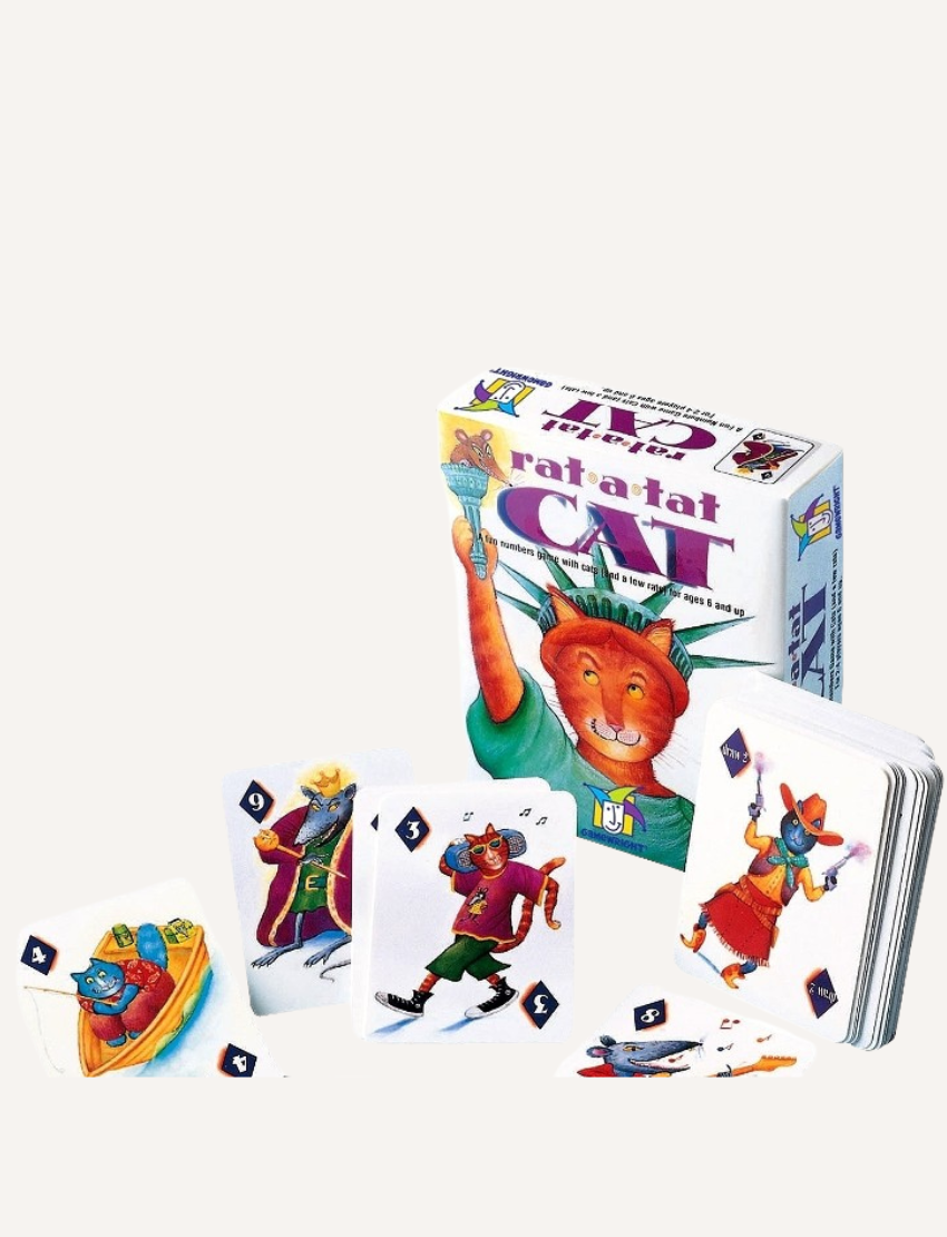 The display showcases the "Rat-A-Tat Cat Card Game" from Jedko Games. The packaging and a selection of illustrated cards featuring cartoon cats are visible, with the cats engaging in activities like skating and donning suits.