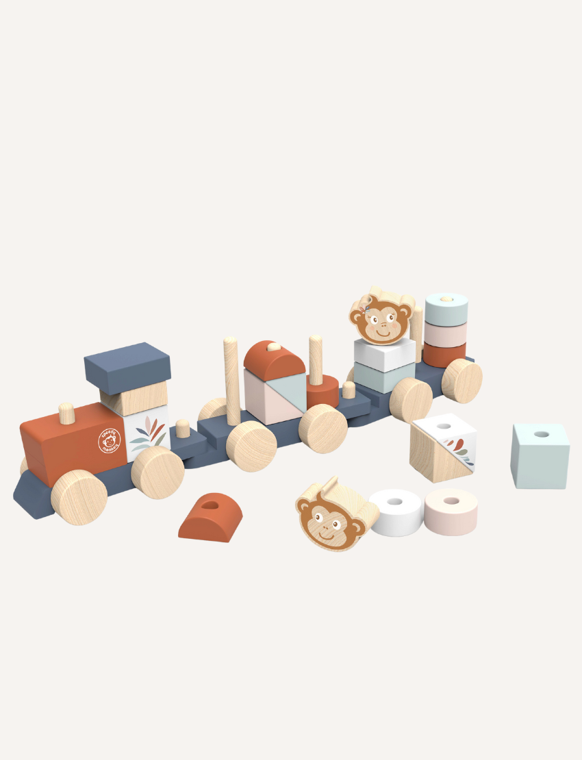 A vibrant Stacking Train by Speedy Monkey is spread across a white surface. The set features various blocks, including a piece with a monkey face, cylindrical shapes, and bright rectangular blocks. Some pieces have wheels attached and are crafted from sustainably sourced wood.