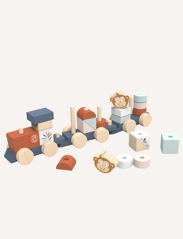 A vibrant Stacking Train by Speedy Monkey is spread across a white surface. The set features various blocks, including a piece with a monkey face, cylindrical shapes, and bright rectangular blocks. Some pieces have wheels attached and are crafted from sustainably sourced wood.