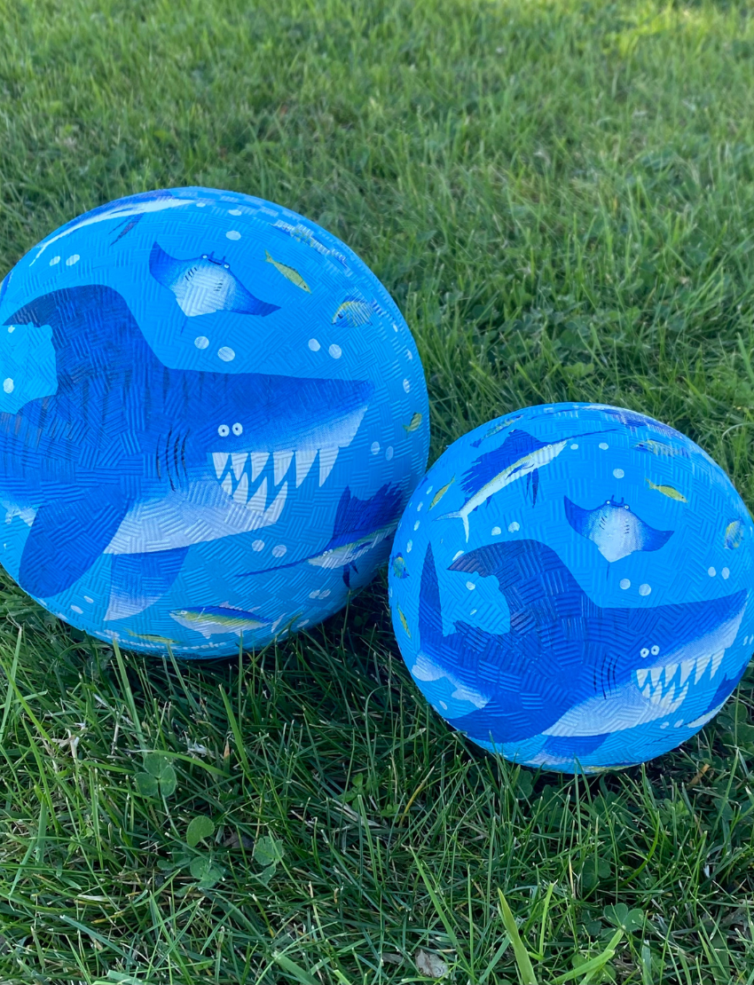 Three Crocodile Creek 7 Inch Playground Balls are displayed: a yellow one with fire trucks, a teal ball with sea creatures like fish and seahorses, and a blue one with shark designs—ideal for boosting children's gross motor skills.