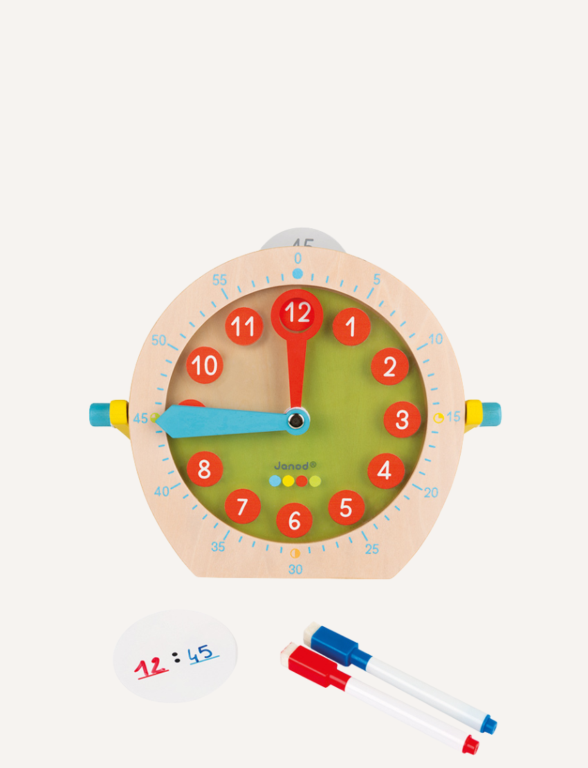 A vibrant educational toy from Janod called "Clock - Learn to tell the time" features a blue clock face and red numbers, encircled by various circular learning attachments. Accompanying this are two markers with caps in red and blue.