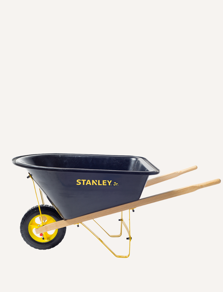 The Stanley Wheelbarrow, a kids' model by Stanley, showcases a sleek black design with vivid yellow accents, a single yellow wheel, and durable wooden handles against a white background.