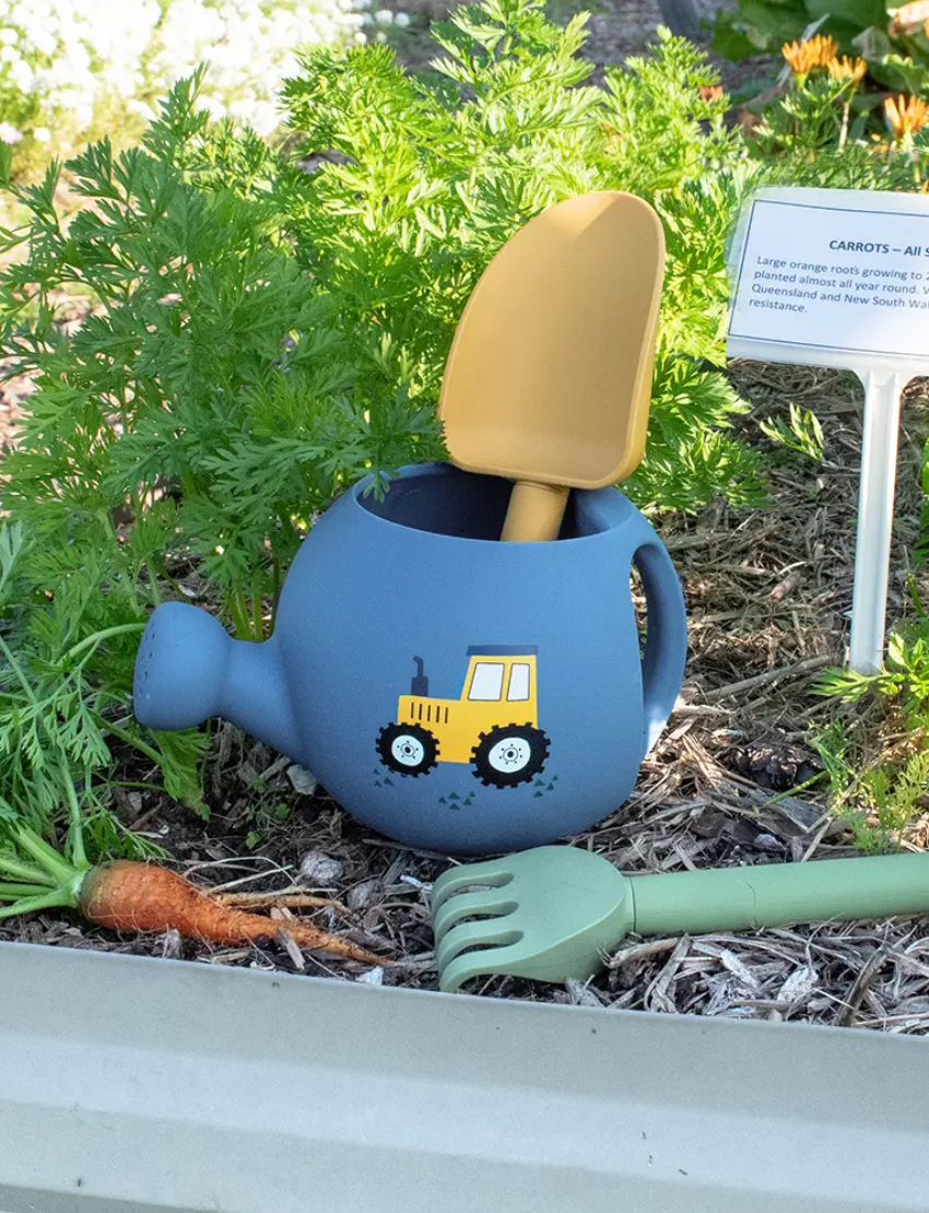 The Playground "My First Gardening Set" includes a blue silicone watering can with a yellow tractor, a green recycled rake, and a yellow spade for an ideal gardening experience.