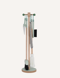 Introducing the Essentials Cleaning Set - Green by Moover, featuring a light wooden stand and a comprehensive set including a mop with white bristles, a brush with black bristles, a dustpan, a gray cloth, and a holder accented in green.