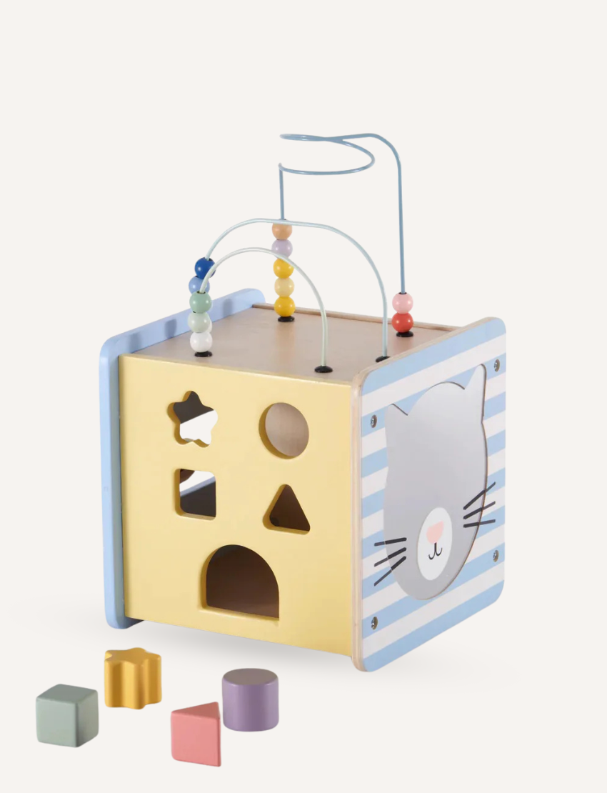 Moover wooden activity cube with shape sorting holes on a yellow side and a cute cat face on a striped blue side.