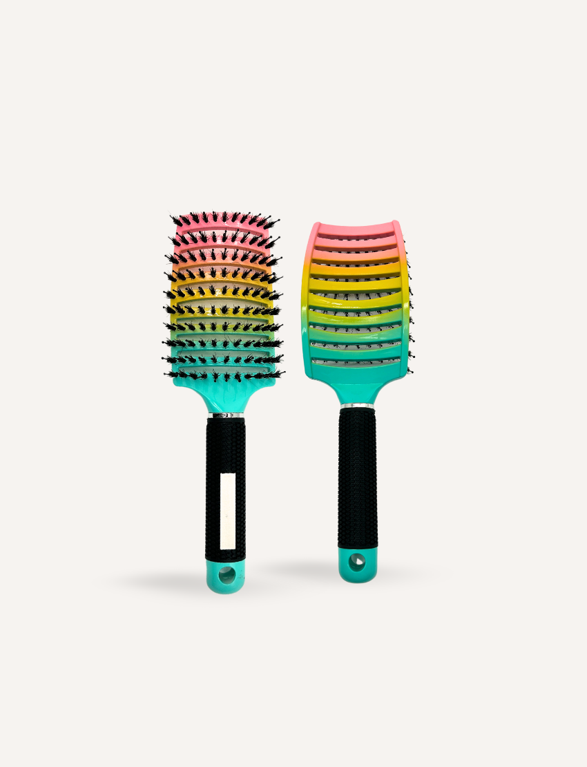 The Melo x SPA Detangle Kit by The Play Way features an open cardboard box with vibrant abstract designs, housing a rainbow-colored hairbrush, a container of blue and white Play Surf Hair Elastics, and a bottle of Dewy Lewy Melo Detangling Spray. This sensory-friendly kit provides everything you need for seamless hair care.