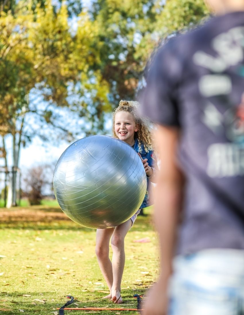 A green box is open, revealing a yellow scooter board, a silver exercise ball, and a set of purple and white "Inchworm" Core Strength Cards, all part of The Play Way's ultimate Core Strength Kit.