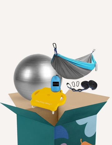 The Play Way's Regulation Through Movement Kit is opened, showcasing a hammock swing with a blue edge, a gray exercise ball, and a yellow scooter board with four casters. Various accessories for sensory regulation can be seen partly inside and around the green and blue box.