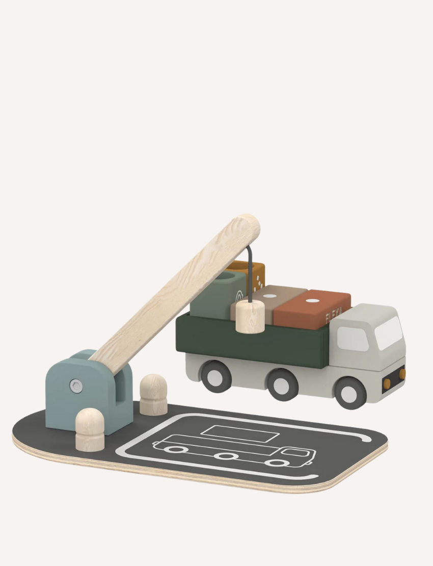 The Flexa Wooden Truck and Crane set includes a truck with block cargo, a balance scale, and two bins marked with recycling symbols. The set features a gray base designed with road patterns and comes with a wooden lever arm. It showcases muted tones of green, brown, and gray.