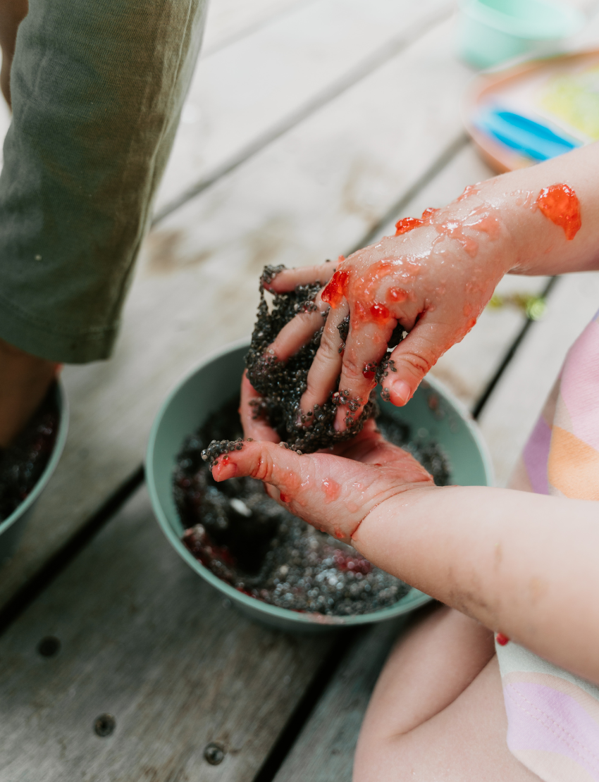 A person holds a Sensory Play Australia card from the "Sensory Play Cards Set in Box" featuring a recipe for "Cloud Dough" and an image of hands holding colorful dough balls. The table also has a whisk, spatula, mixing bowl, measuring cups, and another card from the same set in the background.