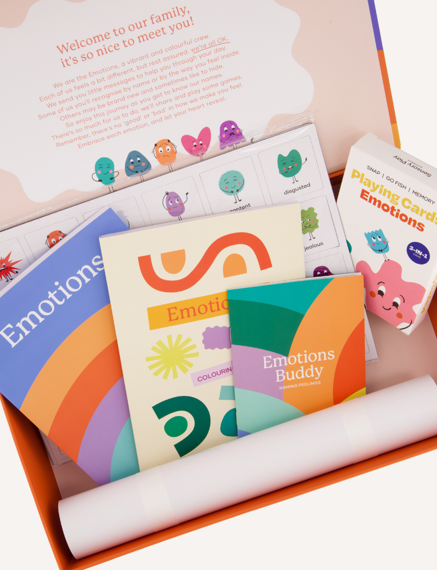 The "Emotions Buddy Naming Feelings Set" by Sensory Play Australia is a colorful box set for children, featuring an empathy-building emotions check-in chart, playing cards labeled "Emotions," a guidebook, and illustrated emotion-themed materials. The packaging is decorated with vibrant rainbow designs.