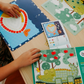 The Therapy At Home Handwriting in Practice Program includes a green and blue box with notebooks, pens, sticky notes, stickers, a pencil sharpener, planner sheets, a black carrying case, and a handwriting workbook for effective practice.
