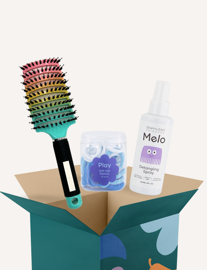 The Play Way hairbrush, elastics, and detangling spray overflowing from a teal box.