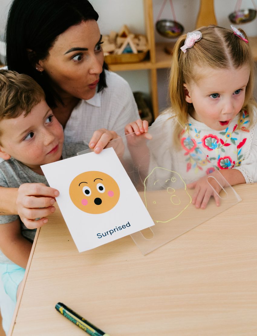 A box of the "What face is that? Game" by Sensory Play Australia is displayed. The front showcases illustrated, interactive faces conveying different emotions, while the side of the box features the title "What face is that?" printed vertically, encouraging kids to explore and role-play various feelings in an enjoyable and engaging manner.