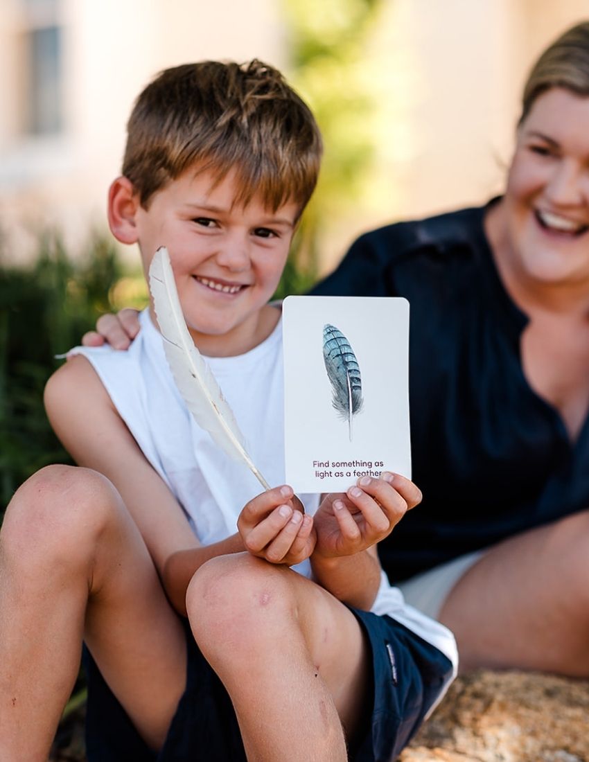 Two cards from the "Scavenger Hunt Cards Set in Box (SPA)" by Sensory Play Australia. The front card displays drawings of a flower, leaf, basketball, and bicycle wheel. The back card is partially visible, showing instructions and icons in various colors designed to promote gross motor skills and physical activity.