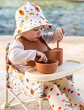 The IZIMINI Cotton Baby Hat is a vibrant bucket hat with a floral print of pink, orange, blue, and green leaves on white. Perfect for outdoor adventures with its wide brim and rounded top, it offers stylish sun protection.