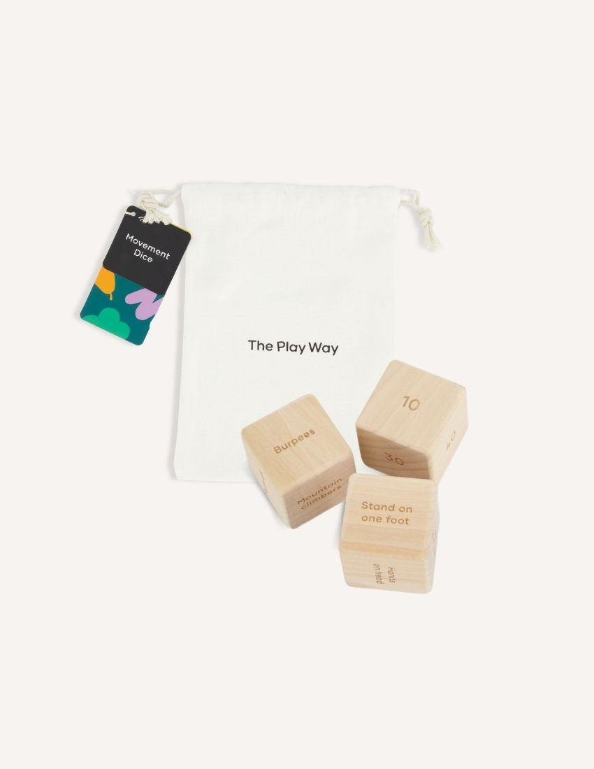 Introducing the Movement Dice Pack by The Play Way: a collection of wooden dice crafted for dynamic exercise routines, presented in a white cloth bag stamped with "The Play Way." Featuring instructions such as "Stand on one foot" alongside numerical values, these dice promote foundational strength through engaging play.