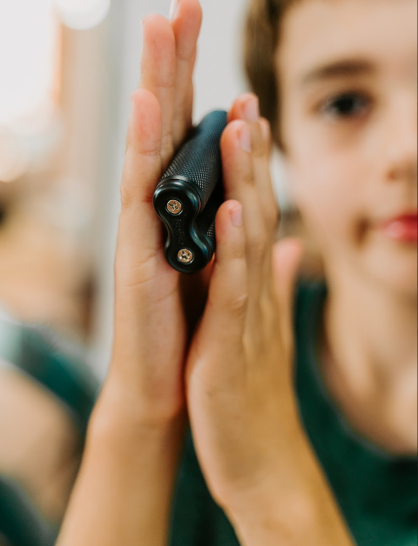 The Kaiko Regulation Fidgets Bundle by The Play Way comes in a black zippered carrying case that opens to reveal various items inside, including a purple silicone fidget, a metallic tool, a keychain, and other small accessories. Ideal for sensory regulation, the interior features a black velvety lining and mesh compartments for organization.