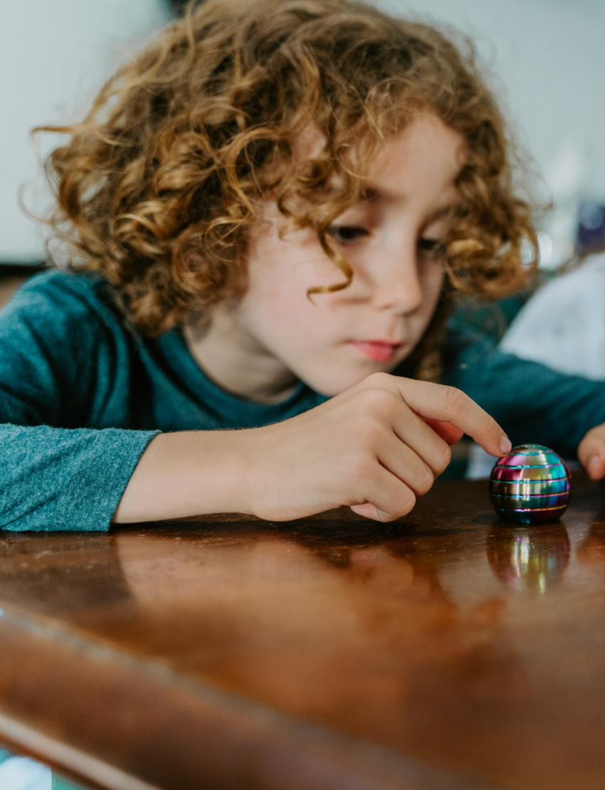 The Kaiko Regulation Fidgets Bundle by The Play Way comes in a black zippered carrying case that opens to reveal various items inside, including a purple silicone fidget, a metallic tool, a keychain, and other small accessories. Ideal for sensory regulation, the interior features a black velvety lining and mesh compartments for organization.