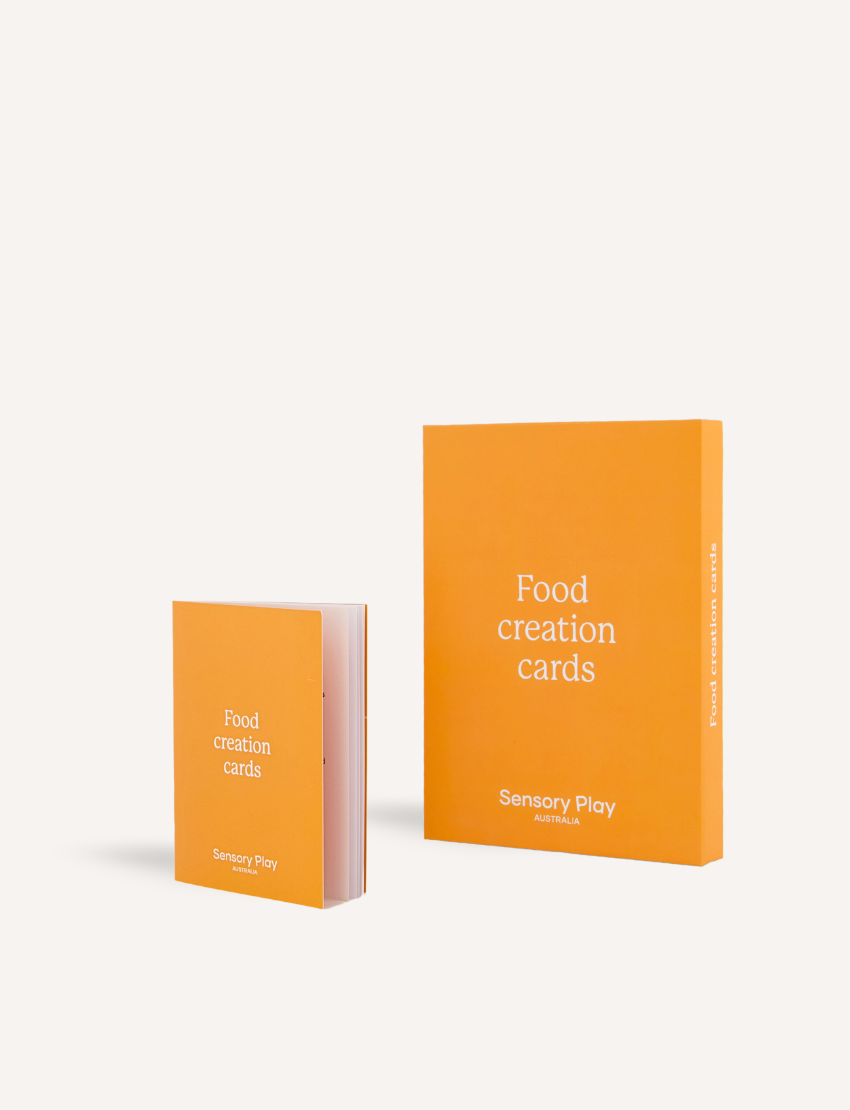 A teal and brown box from The Play Way's Food Exploration Kit, open to display its contents. Inside are a divided plate, utensils, a booklet titled "Food Creation Cards," two kitchen utensils, an orange pop-it toy for sensory preferences, a rolling pin set, and various cards labeled "Food Investigator." It's the ultimate Food Exploration Kit.