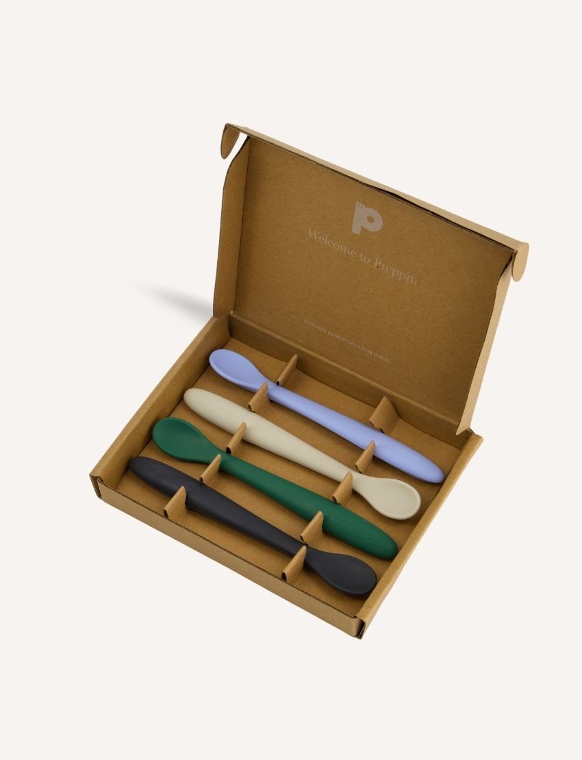 Open Preppit box revealing a set of four silicone baby spoons in pastel colors (lavender, cream, green, black), with the Preppit logo inside.