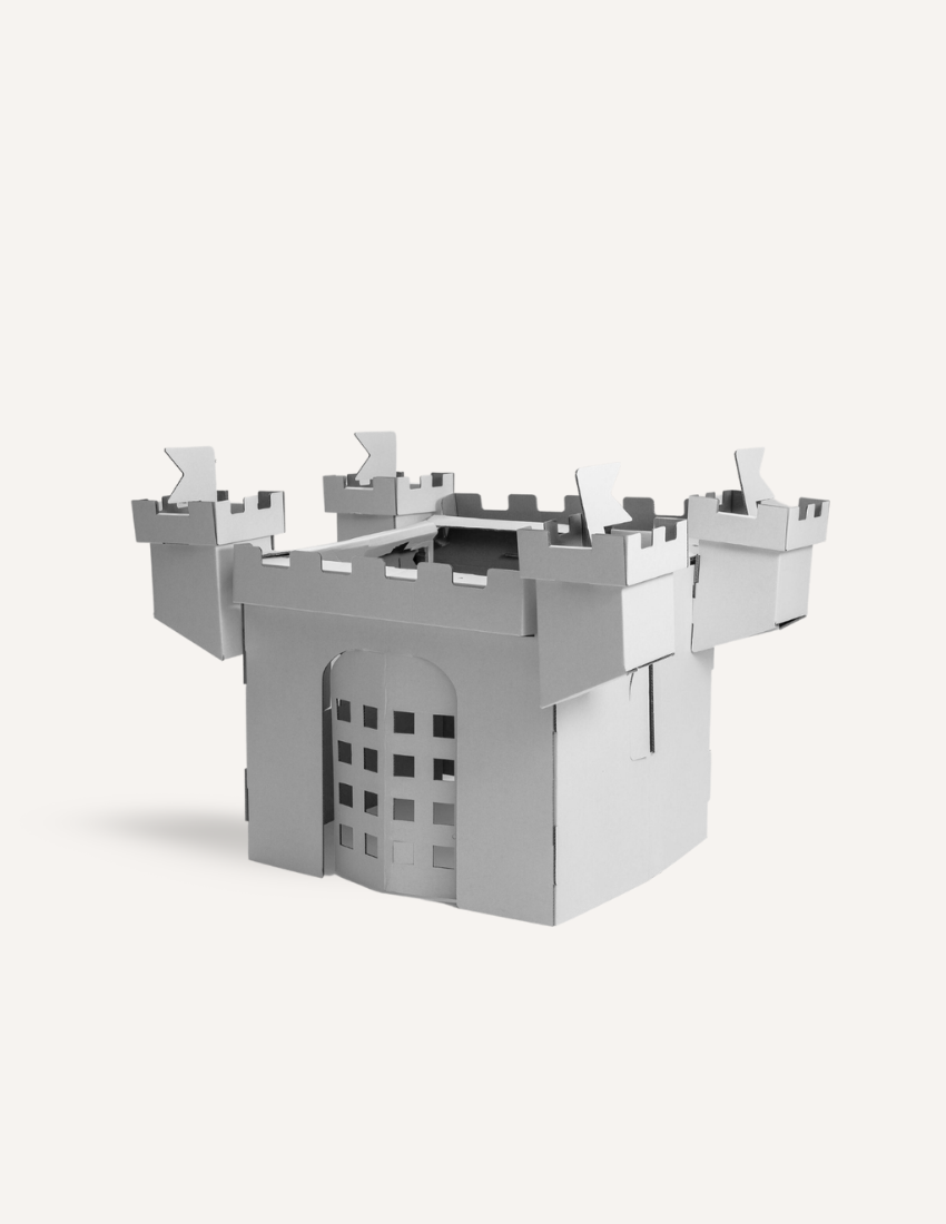 The Castle House by Les Petite Artistes is a straightforward, gray, cardboard model of a medieval-style castle. It boasts a crenelated top and four corner towers, along with an arched entrance adorned with a grid-like pattern at the front. The background is plain white.