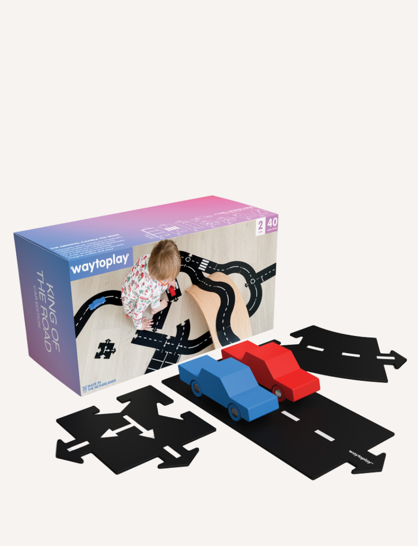 The image displays the "King Of The Road Car Edition" toy set by Waytoplay, which includes flexible road pieces and two wooden cars in red and blue. In the background, there is a box depicting a child playing with and assembling the road.