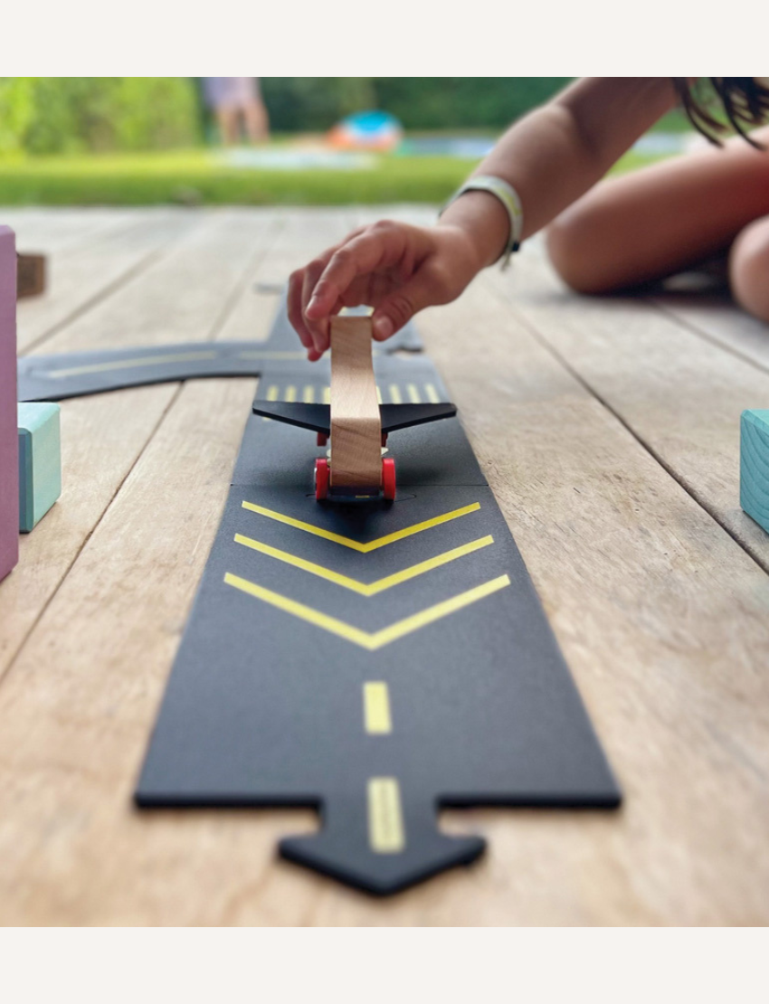 A set featuring Waytoplay's "Runway" includes a wooden toy airplane along with multiple interlocking black road pieces adorned with yellow markings. The display depicts a runway path, and the packaging showcases an illustration of the assembled product.