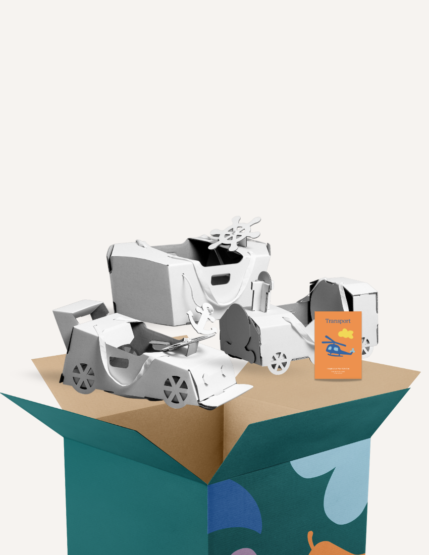 A plain white background sets the stage for an image showcasing a cardboard box, which is surrounded by various white cardboard models of vehicles. A small card labeled "Transport Kit" from The Play Way, featuring illustrations of an airplane and a car, is also visible near the models, making it perfect for imaginative play.