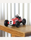 The Verve Loretino Marino toy car by Playforever is displayed against a plain white background. This stylish red race car, with black wheels and the number 5 on its front, boasts a sleek design and features a small driver's seat with a silver helmet.