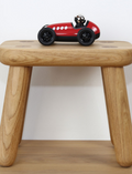 The Verve Loretino Marino toy car by Playforever is displayed against a plain white background. This stylish red race car, with black wheels and the number 5 on its front, boasts a sleek design and features a small driver's seat with a silver helmet.