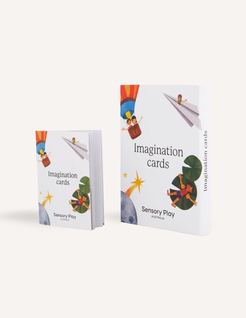 Two white boxes labeled "Imagination Cards Set in Box" by Sensory Play Australia are shown. The larger box is on the right, and the smaller box is on the left. The boxes feature illustrations of children engaging in imaginative activities, perfect for enhancing storytelling skills with a colorful background.