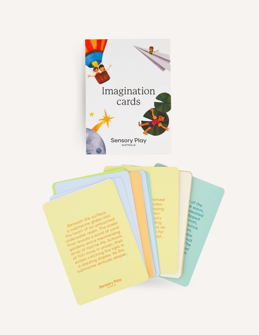 Two white boxes labeled "Imagination Cards Set in Box" by Sensory Play Australia are shown. The larger box is on the right, and the smaller box is on the left. The boxes feature illustrations of children engaging in imaginative activities, perfect for enhancing storytelling skills with a colorful background.