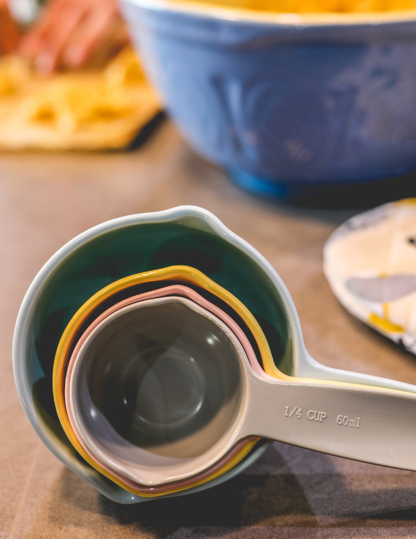 The "Getting Started with Baking Kit" by The Play Way is open. Inside this children's baking kit, you'll find a black apron and a black towel, both featuring "The Play Way" branding, colorful measuring cups, a recipe sheet for culinary adventures, and a black muffin tray.