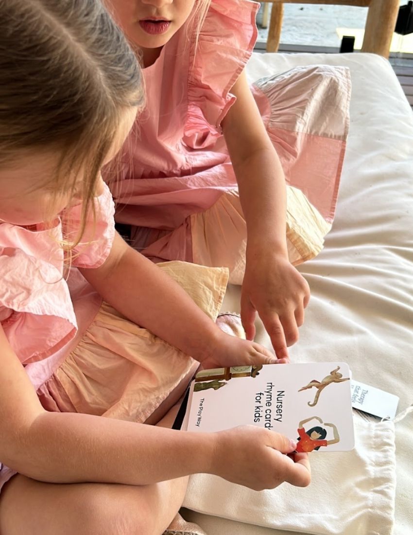 Two young girls looking at and holding Nursery Rhyme Cards from The Play Way.