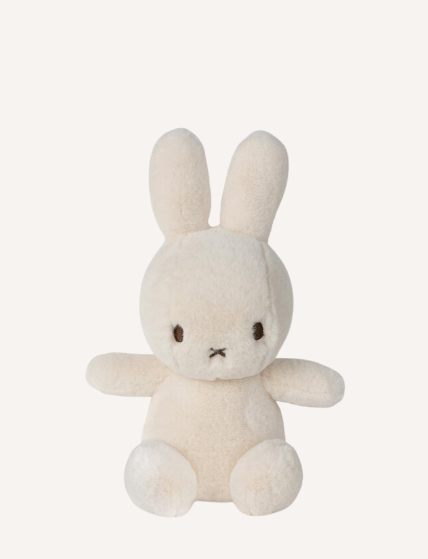 Two Miffy "Cozy Miffy" plush bunnies are showcased against a plain background. The left one is light cream, while the right is dark gray; both are made from recycled polyester and feature simple facial details with small black eyes and a cross-shaped nose and mouth.