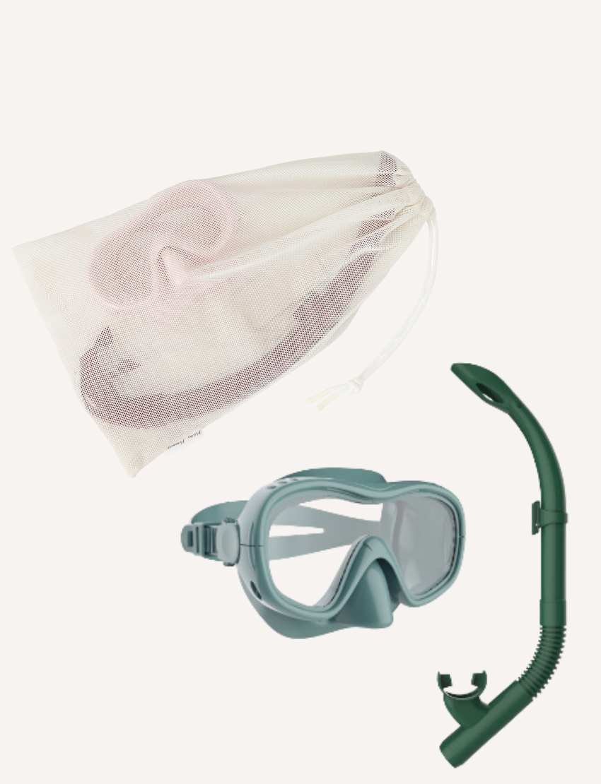 The Petites Pommes Betty Snorkelling Set features a wide-vision, adjustable mask in vibrant green and an easy-breathe snorkel with a sleek curve. It comes with a white mesh drawstring bag, ensuring comfort and clarity, beautifully arranged on a pristine white background.