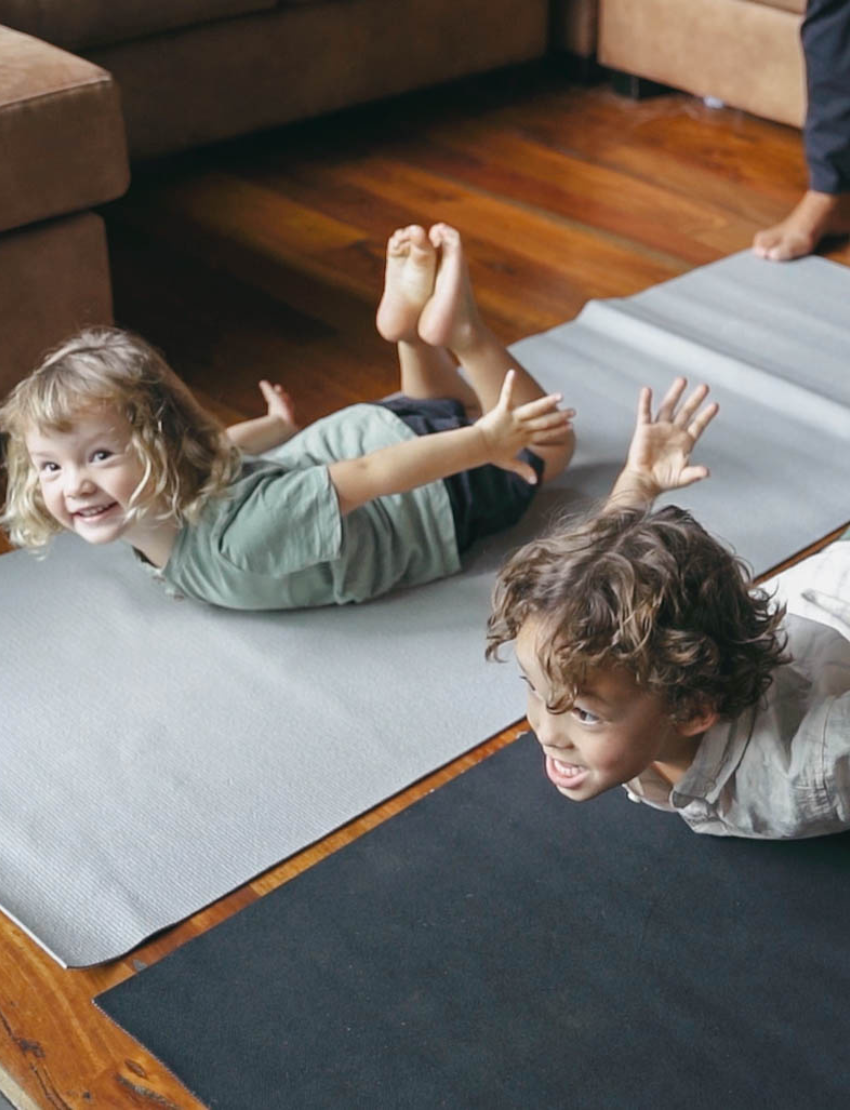 The Yoga & Mindfulness Program by Therapy At Home features an open teal box with abstract designs, holding a yoga mat, teal cushion, books, cards, and small items—perfect for home yoga and mindfulness—displayed upright against a simple background.