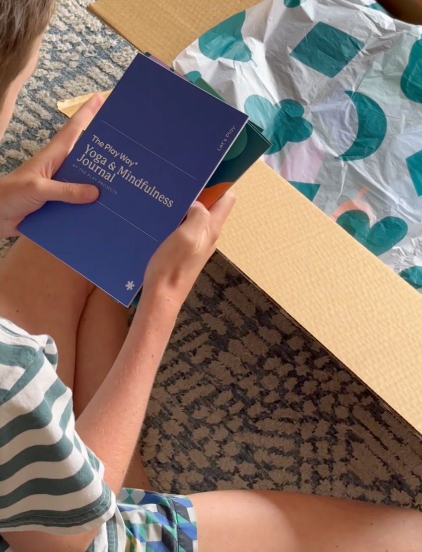 The Yoga & Mindfulness Program by Therapy At Home features an open teal box with abstract designs, holding a yoga mat, teal cushion, books, cards, and small items—perfect for home yoga and mindfulness—displayed upright against a simple background.