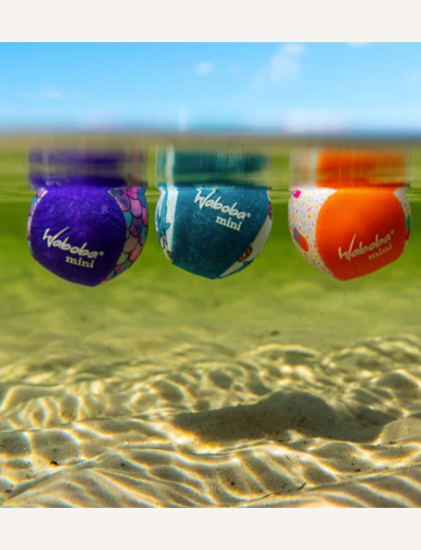 The Mini Twin Pack Water Bounce Balls packaging by Waboba features two colorful spheres, one in yellow and the other in teal, along with the catchy tagline "Bounces on Water!" The design is set against a beach scene with waves, and this pack promises "Double the fun" for playtime at oceans and lakes.