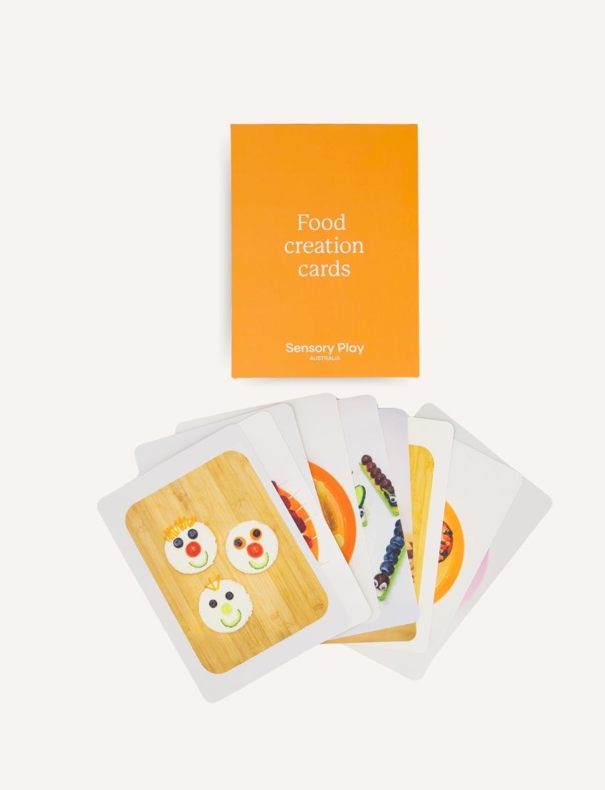 The Lunch Box Creation Kit from The Play Way includes an open box filled with colorful food creation cards, an assortment of cookie cutters in various shapes, sensory play materials, a lunch box book, and a package adorned with food-related designs. These items are perfect for engaging in creative, food-themed activities.